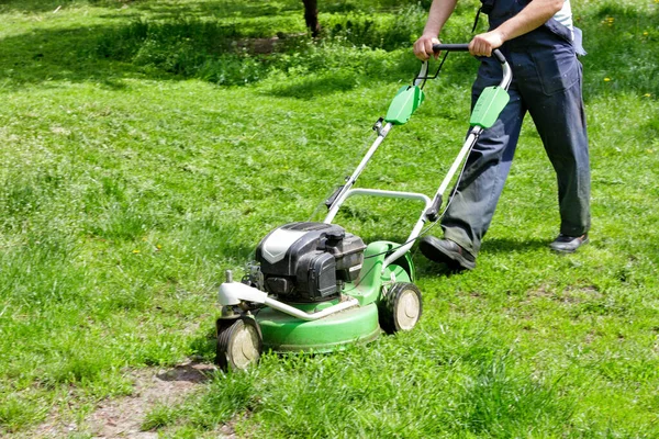 都市公園に芝刈り機を持った労働者が芝生を刈る — ストック写真