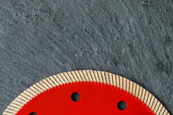 The red diamond cutting professional circle segment with a thin blade and flange is used for precise cutting of material against a gray granite background, image with copy space.