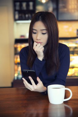 Smartphone ile düşünme bir Asyalı kadın 