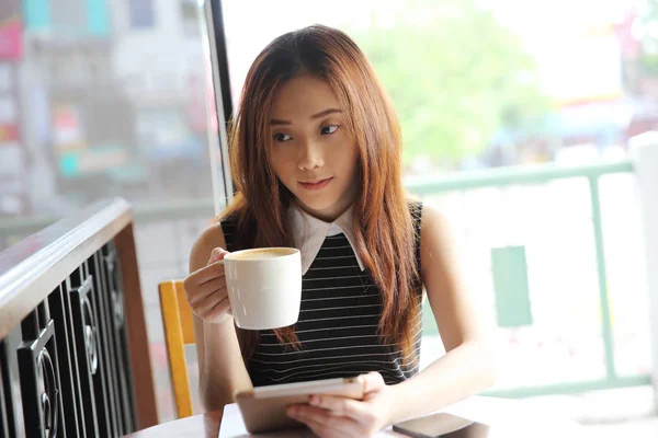 Asijské žena pití kávy s tabletem — Stock fotografie