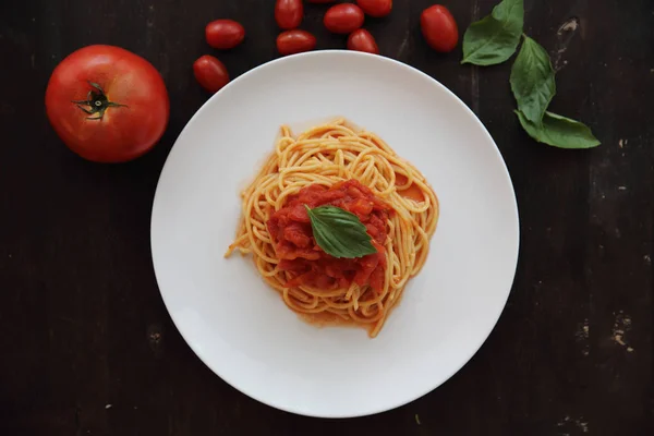 Espaguetis con salsa de tomate y albahaca en fondo de madera oscura — Foto de Stock