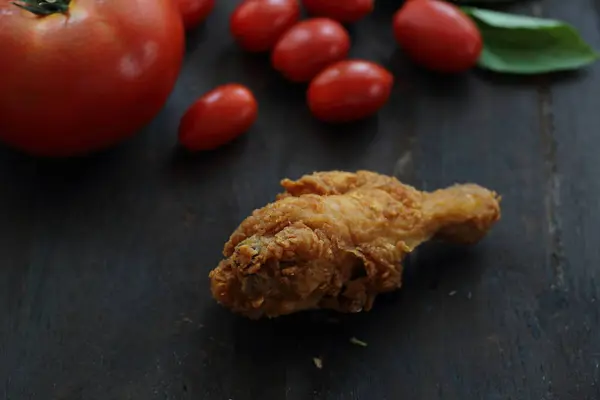 Smażony kurczak z pomidorów w przyciemnić tło drewna — Zdjęcie stockowe