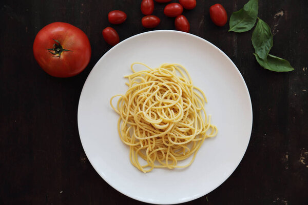 Макаронная лапша с томатным соусом и базилик в темной деревянной спине
