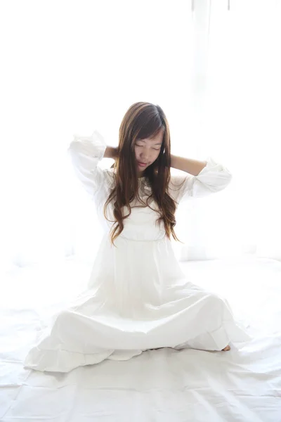 Asiática joven mujer despertar con almohada en blanco habitación —  Fotos de Stock
