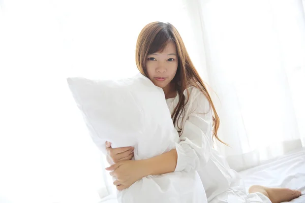 Ázsiai fiatal nő nyomdokvíz-megjelöl-val párna fehér szobában — Stock Fotó