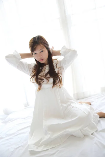 Asiatico giovane donna wake up con cuscino in bianco stanza — Foto Stock