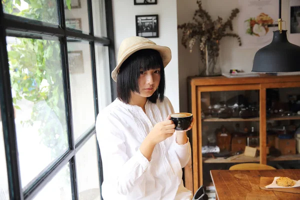 Asiatisk ung kvinna dricker kaffe stående med i kafé — Stockfoto