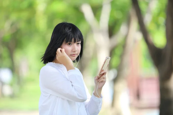 Asian young woman listening music on smart phone portrait with g — Stock Photo, Image