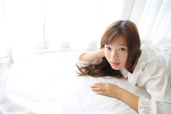 Азиатская девушка просыпается с подушкой в белой комнате — стоковое фото