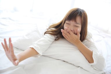 Asyalı genç kadın beyaz oda yastık ile uyan
