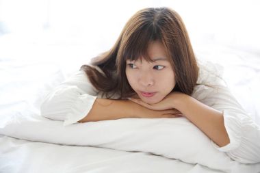 Asyalı genç kadın beyaz oda yastık ile uyan