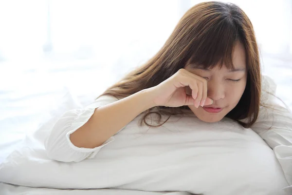 Asiática joven mujer despertar con almohada en blanco habitación —  Fotos de Stock