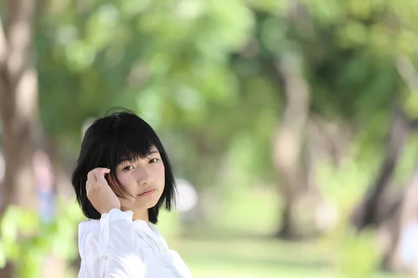 Aziatische jonge vrouw denken en op zoek portret met groene boom — Stockfoto