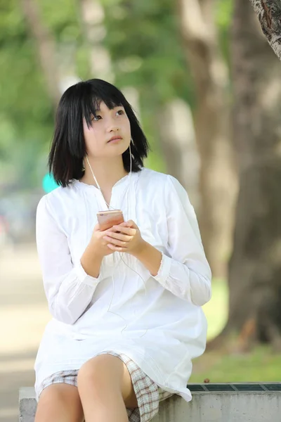 Mujer joven asiática escuchando música en retrato de teléfono inteligente con g — Foto de Stock