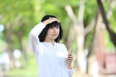 Asyalı genç kadın üzerinde akıllı telefon portre g ile müzik dinleme