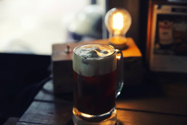 Coffee cocktail with coffee bean and rosemary on top with wood b