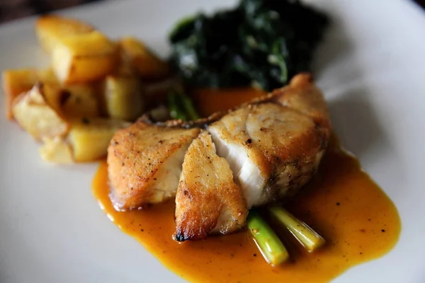 Filete de lubina con patatas y espinacas en salsa de limón — Foto de Stock