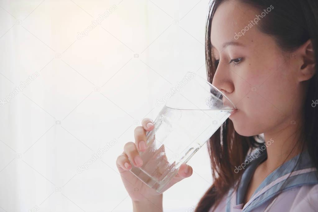 School girl drinking water on white room