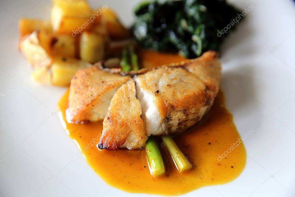 Sea bass fillet steak with potatoes and spinach in lemon sauce 