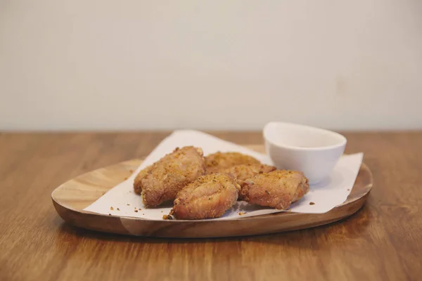 Ailes de poulet frit sur fond de bois avec lumière du restaurant — Photo