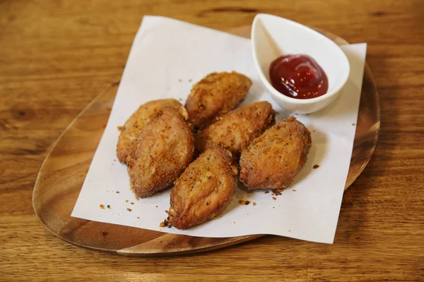 Ailes de poulet frit sur fond de bois avec lumière du restaurant — Photo