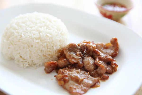 Cerdo frito con ajo y arroz sobre fondo de madera, comida tailandesa —  Fotos de Stock