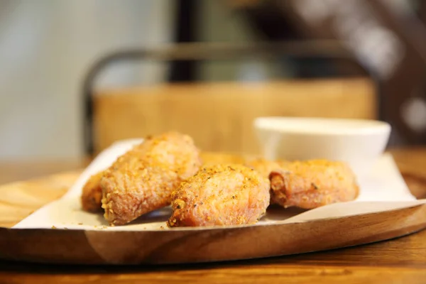 Ailes de poulet frit sur fond de bois avec lumière du restaurant — Photo