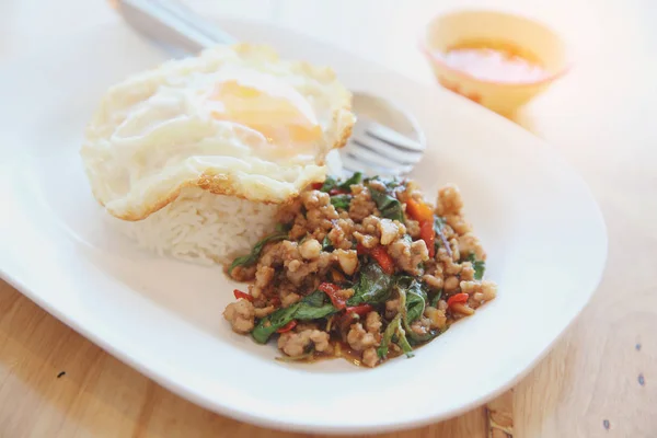 Stir fried pork and basil with rice and egg on wood background t — Stock Photo, Image