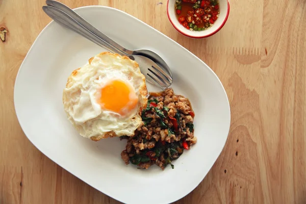 Kızarmış domuz eti ve fesleğen ile pirinç ilave edin ve ahşap arka plan t üzerinde yumurta