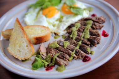 Izgara sığır eti biftek ile kızarmış ekmek, kızarmış yumurta ve sebze üzerine 