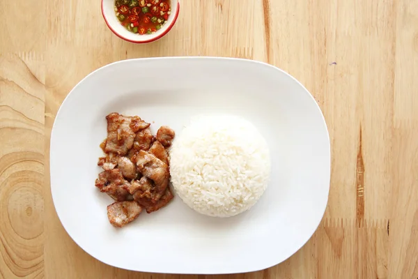 หมูทอดกับกระเทียมและข้าวบนพื้นหลังไม้ อาหารไทย — ภาพถ่ายสต็อก