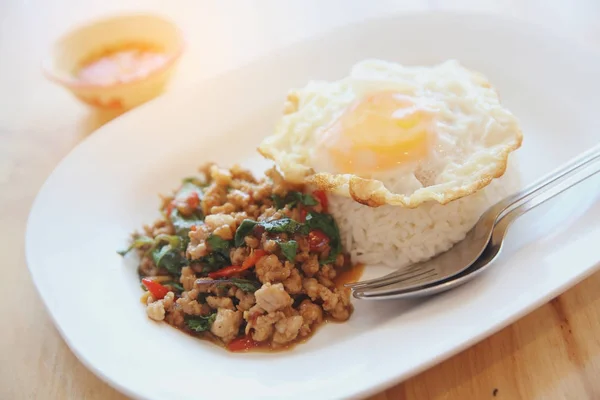 Stir fried pork and basil with rice and egg on wood background t — Stock Photo, Image