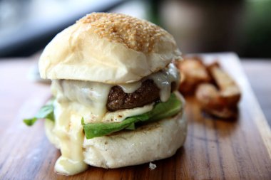 Sığır eti hamburger ile peynir ve ahşap arka plan üzerinde yangınları