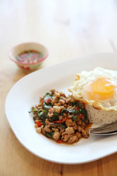 Stir fried pork and basil with rice and egg on wood background t — Stock Photo, Image