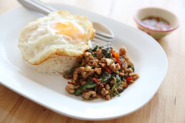 Kızarmış domuz eti ve fesleğen ile pirinç ilave edin ve ahşap arka plan t üzerinde yumurta