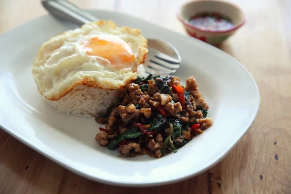 Revuelva la carne de cerdo frita y la albahaca con arroz y huevo sobre fondo de madera t — Foto de Stock