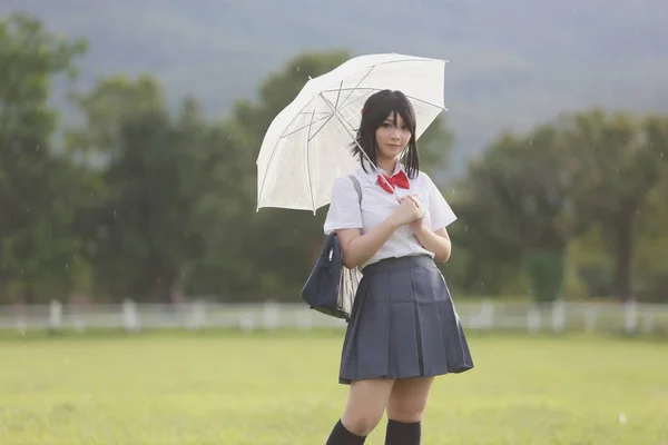 Japanse school met paraplu op regen in platteland met gras — Stockfoto