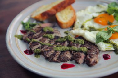 Izgara sığır eti biftek ile kızarmış ekmek, kızarmış yumurta ve sebze üzerine 