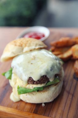 Sığır eti hamburger ile peynir ve ahşap arka plan üzerinde yangınları