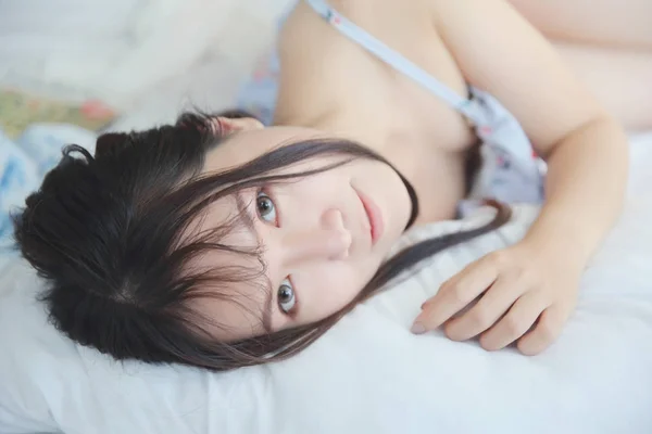 Молодая азиатка в спальне с белым тоном — стоковое фото