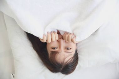 Asyalı genç kadın yatakta beyaz ses tonuyla uyan