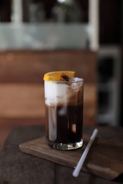 Café preto de gelo com laranja sobre fundo de madeira — Fotografia de Stock