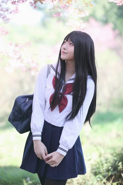 Escola japonesa menina vestido com sakura flor natureza passarela — Fotografia de Stock