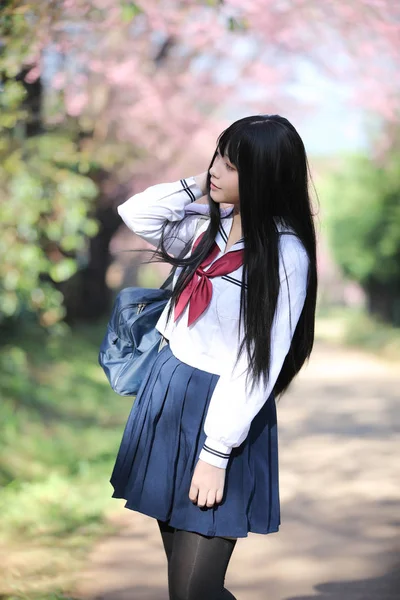 Escola japonesa menina vestido com sakura flor natureza passarela — Fotografia de Stock