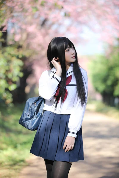 Japanese school girl dress with sakura flower nature walkway — Stock Photo, Image