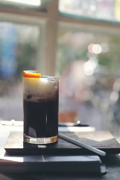 Turuncu ahşap arka plan üzerinde siyah kahve buz — Stok fotoğraf