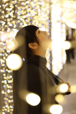 Bokeh backg üzerinde siyah pamuklu kazak giyen genç güzel kız