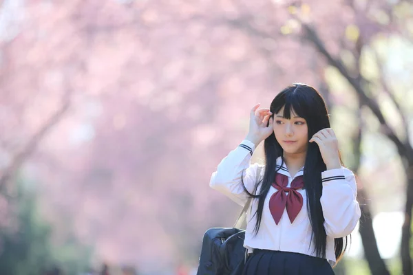 Japonais école fille robe avec sakura fleur nature passerelle — Photo