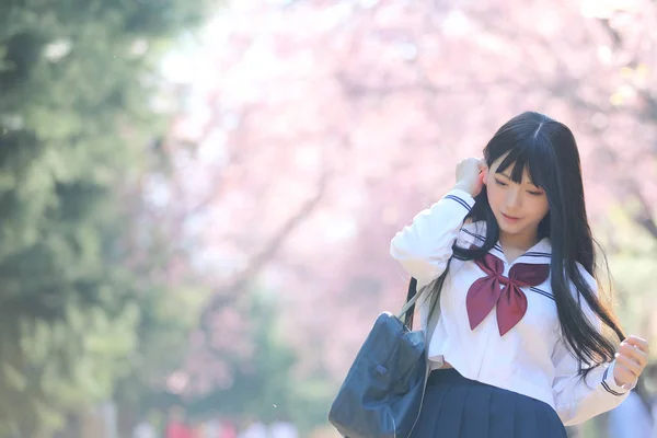 Ιαπωνικό σχολείο κορίτσι φόρεμα με λουλούδι sakura φύση διάδρομος — Φωτογραφία Αρχείου