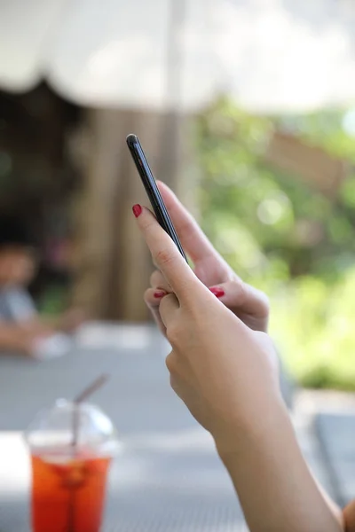 Female hand with smartphone trading stock online in outdoor coffee shop , Business concept